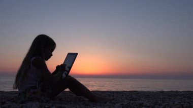 plajda, Sunset View kız siluet akıllı telefonlar kullanarak 4 k çocuk oynamaya Tablet