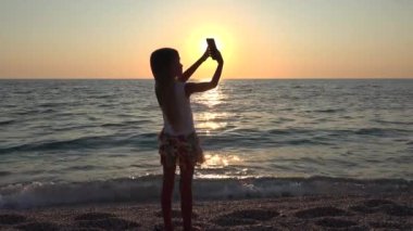 4k kız alma Selfie yolu ile Smartphone, plaj görünümü batımında, Tablet oynayan çocuk