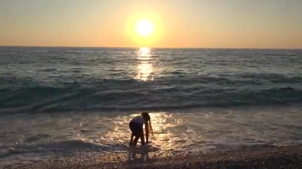 在日落的海滩上玩耍的女孩 快乐的孩子漫步在海边的海浪中 — 图库视频影像