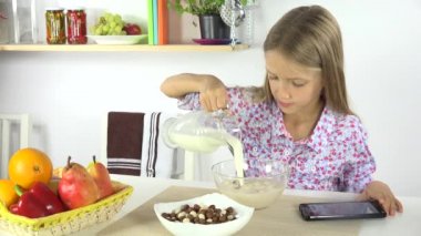 Tablet oynarken, tahıllar ile kahvaltıda süt, Kız 4 k mutfakta yemek çocuk
