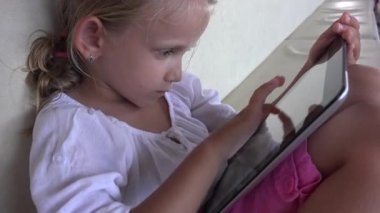 4k Tablet kanepe üzerinde oynayan çocuk kız kullanarak akıllı telefonlar, çocuklar yastıkları öğrenme