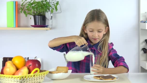 Kind trinkt Milch beim Frühstück, Mädchen isst Brot und Schokolade in der Küche 4k