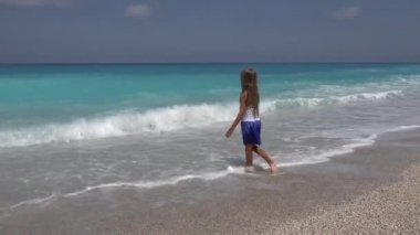 Kumsalda, oynayan çocuk evlat iplik içinde dalgalar deniz, sahil şeridi, gün batımı görünümü üzerinde suda küçük kız