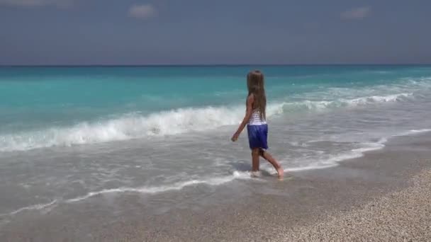 在沙滩上玩耍的孩子 在海浪中旋转的孩子 在海岸线上的水中的小女孩 日落的景色 — 图库视频影像