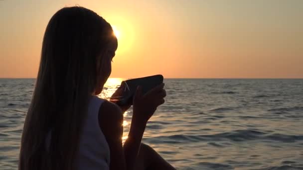 Flicka Spela Surfplatta Stranden Vid Solnedgången Barn Med Smartphone Havsstranden — Stockvideo