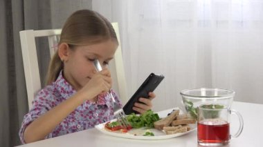 Çocuk oynamaya Tablet, yeme, kız yiyor kahvaltı mutfak 4k iken Smartphone