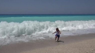 4 k kız plajda, mutlu çocuk çalışan deniz dalgaları yaz aylarında sahil şeridi üzerinde oynama