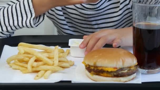 子供のレストランでハンバーガーを食べる子供が食べる迷惑ファーストフード空腹少女 — ストック動画