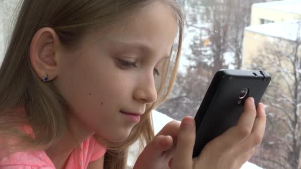 子ウィンドウ 女の子のゲームをプレイしてお友達にメッセージを送信するスマート フォンを使用して — ストック動画