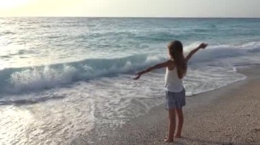 Kumsalda oynarken, deniz dalgaları, seyretmekten çocuk kız sahil şeridi üzerinde yaz aylarında iplik