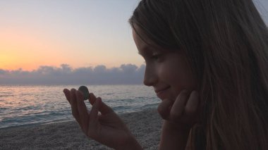 Plajda, çocuk evlat kıyıda oynayan'nde günbatımı, eğitim çakıl izlerken kız