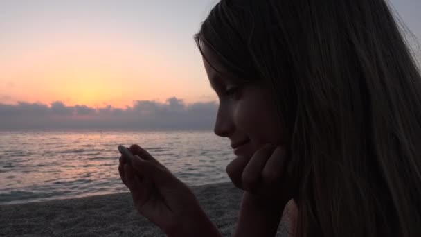 Dziecko na plaży, dzieciak bawiący się na brzegu, w zachód słońca, Dziewczyna oglądając studia kamyki — Wideo stockowe