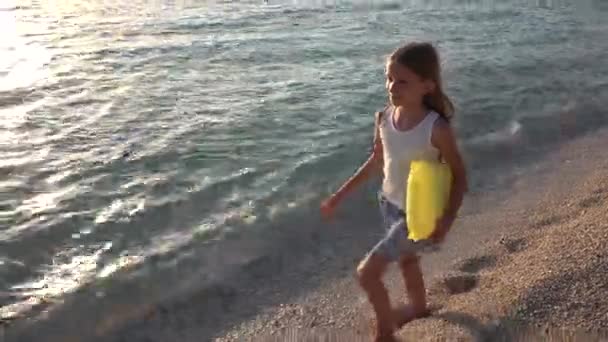 Enfant jouant sur la plage au coucher du soleil, fille heureuse marchant dans les vagues de la mer sur le bord de la mer — Video