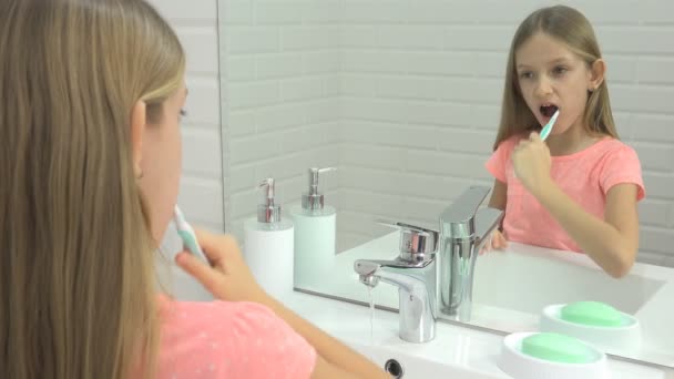 Kind putzt Babyzähne im Badezimmer, Mädchen wäscht sich mit Zahnbürste, Kind im Spiegel — Stockvideo