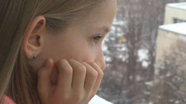 悲しい子ウィンドウ 不幸な思いやりのある女の子の顔 雪が降る冬の日を — ストック写真