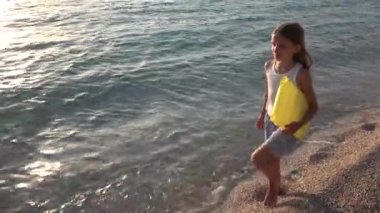 Kumsalda gün batımında, deniz dalgaları kız deniz yürüme çocuk mutlu oynayan çocuk
