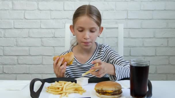 子供のレストランでハンバーガーを食べる子供が食べる迷惑ファーストフード 女の子味フライド ポテト — ストック動画