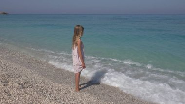 Plajda, kız dalgalar deniz, sahil üzerinde izlerken çocuk oynayan çocuk