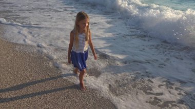 Kumsalda gün batımında, deniz dalgaları kız deniz yürüme çocuk mutlu oynayan çocuk