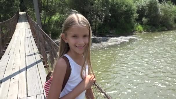 孩子在山上的桥梁 孩子徒步在自然 女孩看着一条河 — 图库视频影像
