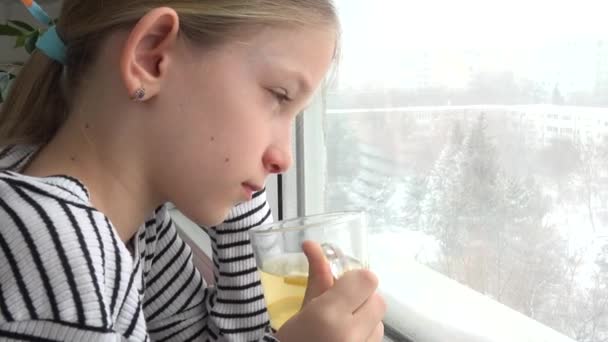 病気の子供を吹雪の冬茶を飲むウィンドウ 病気悲しい子供の顔を見て — ストック動画