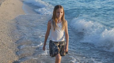 Kumsalda gün batımında, deniz dalgaları kız deniz yürüme çocuk mutlu oynayan çocuk