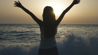 Gün batımında, deniz kıyısı üzerinde kız siluet seyir dalgalar çocuk kumsalda, oynayan çocuk