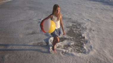 Kumsalda gün batımında, deniz dalgaları kız deniz yürüme çocuk mutlu oynayan çocuk