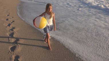 Kumsalda gün batımında, deniz dalgaları kız deniz yürüme çocuk mutlu oynayan çocuk