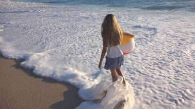 Kumsalda gün batımında, deniz dalgaları kız deniz yürüme çocuk mutlu oynayan çocuk