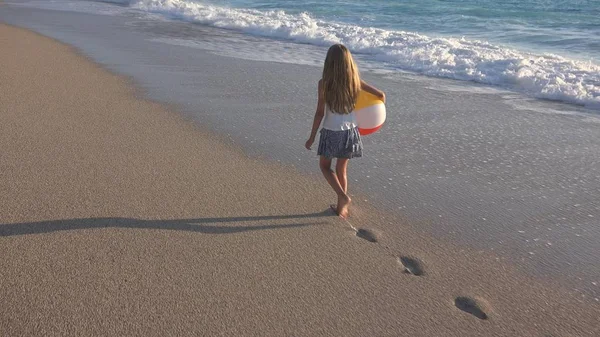 Kumsalda gün batımında, deniz dalgaları kız deniz yürüme çocuk mutlu oynayan çocuk