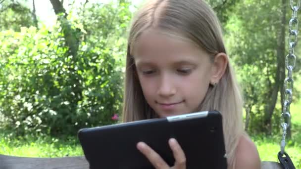 Niño Jugando Tablet Swinging Chica Utiliza Aire Libre Naturaleza Niño — Vídeos de Stock