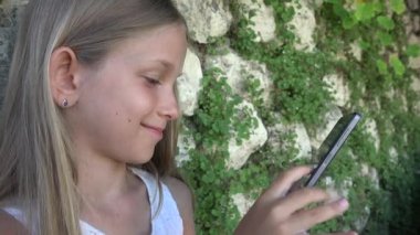 Taş duvar tarafından Smartphone kız bahçede oynayan çocuk Tablet, çocuk açık kullanır