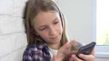 Oynarken Tablet, çocuk kullanır Smartphone, kız okuma mesajları Internet üzerinden çocuk