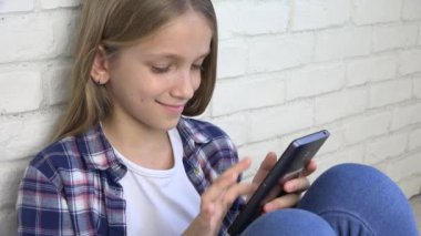 Oynarken Tablet, çocuk kullanır Smartphone, kız okuma mesajları Internet üzerinden çocuk