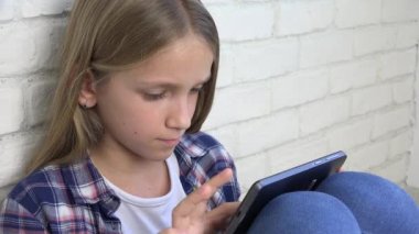 Oynarken Tablet, çocuk kullanır Smartphone, kız okuma mesajları Internet üzerinden çocuk