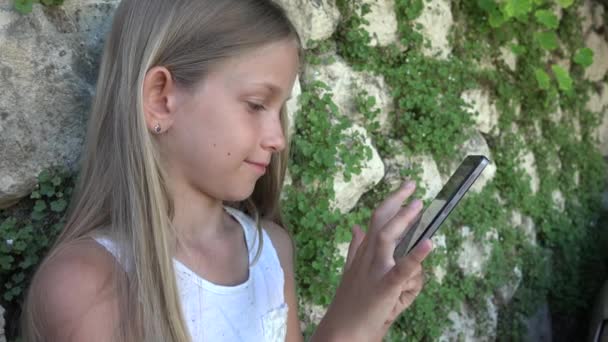 Criança Jogando Smartphone Por Parede Pedra Quintal Menina Usa Tablet — Vídeo de Stock