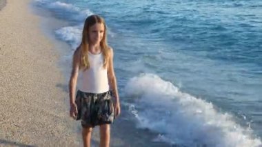 Kumsalda gün batımında, deniz dalgaları kız deniz yürüme çocuk mutlu oynayan çocuk