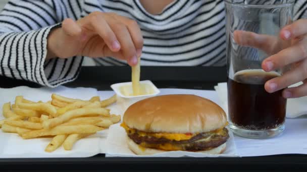 ファーストフードを食べ 子供の子供がジュースを飲む女の子のレストランでハンバーガーを食べる — ストック動画