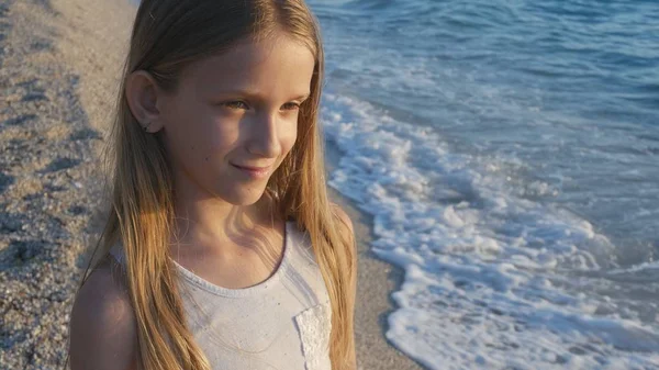 Kind spielt am Strand bei Sonnenuntergang, Kind beobachtet Meereswellen, Mädchenporträt an Land — Stockfoto