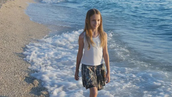 Gyermek játszik tengerparton naplementekor, boldog gyerek tengeri hullámok lány sétál a tengerparton — Stock Fotó