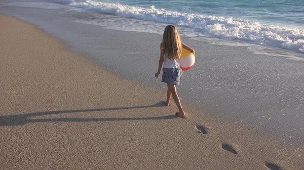 Дитина грав на пляжі на заході сонця, щасливого малюка, ходьба у морських хвилях дівчину на березі моря — стокове фото