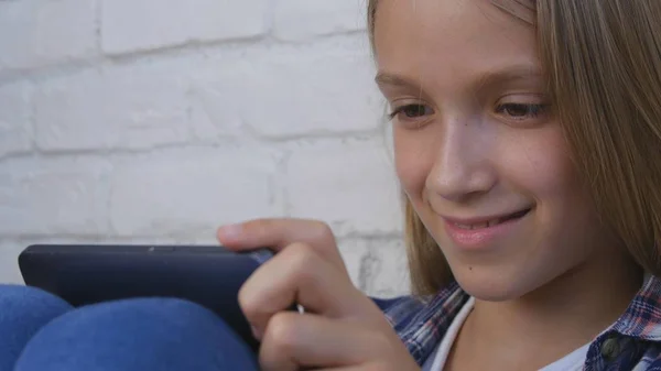 Gyermek játszik tabletta, Smartphone, gyerek lány üzenetek olvasása az interneten való böngészés — Stock Fotó