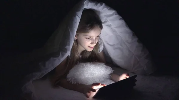 Gyermek játszik tabletta a sötét éjszakában, lány, Internet böngészés az ágyban, nem alszik — Stock Fotó