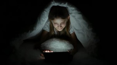 Tablet karanlık gecede, kız yatakta uyumuyor Internet tarama oynayan çocuk