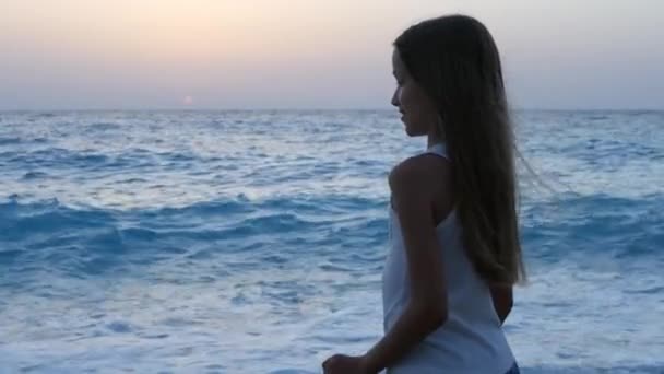 Copilul se joacă pe plajă în Apus de soare, Copilul se uită la valurile de mare, Portretul fetelor pe țărm — Videoclip de stoc