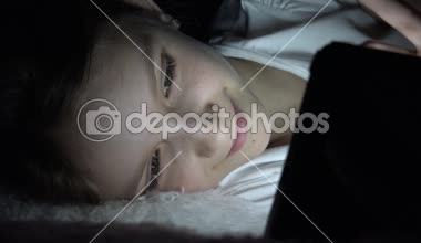 Tablet karanlık gecede, kız yatakta uyumuyor Internet tarama oynayan çocuk