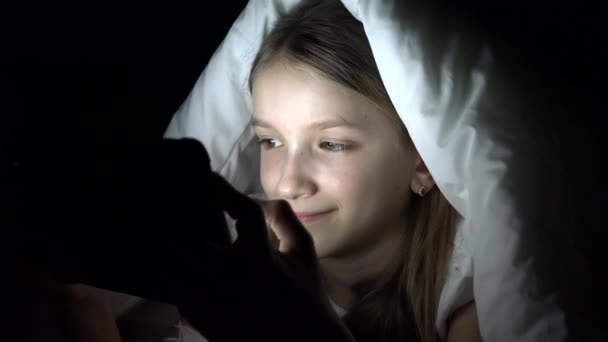 儿童玩平板电脑在黑暗的夜晚, 女孩浏览互联网在床上, 而不是睡觉 — 图库视频影像