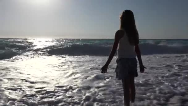 Дитина грав на пляжі на захід сонця, дитина дивиться морські хвилі, портрет дівчині на березі — стокове відео