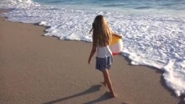 Kumsalda gün batımında, deniz dalgaları kız deniz yürüme çocuk mutlu oynayan çocuk